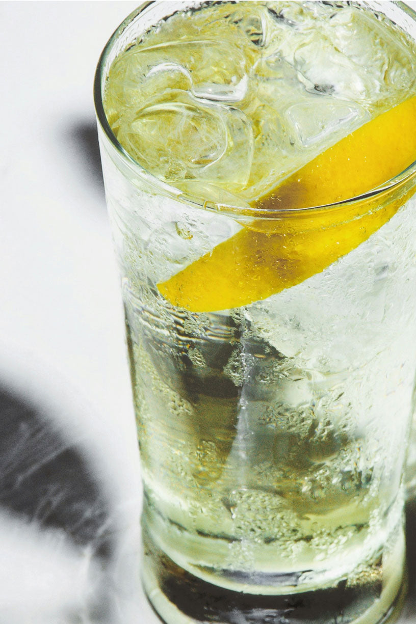 Clear glass with a lemon wedge and ice cubes on a light background